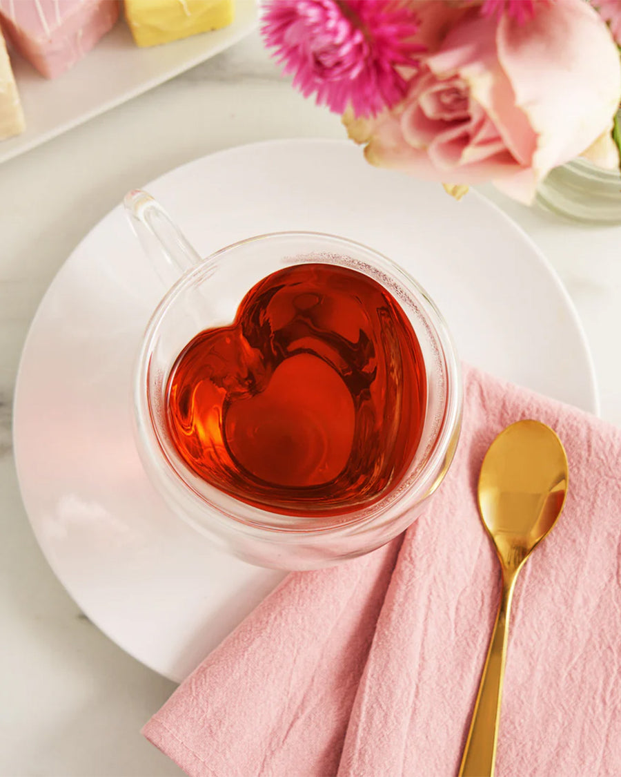 heart shaped clear glass mug with red tea inside on a table display