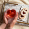 model holding heart shaped clear glass mug with red tea inside on a table display with red tea inside