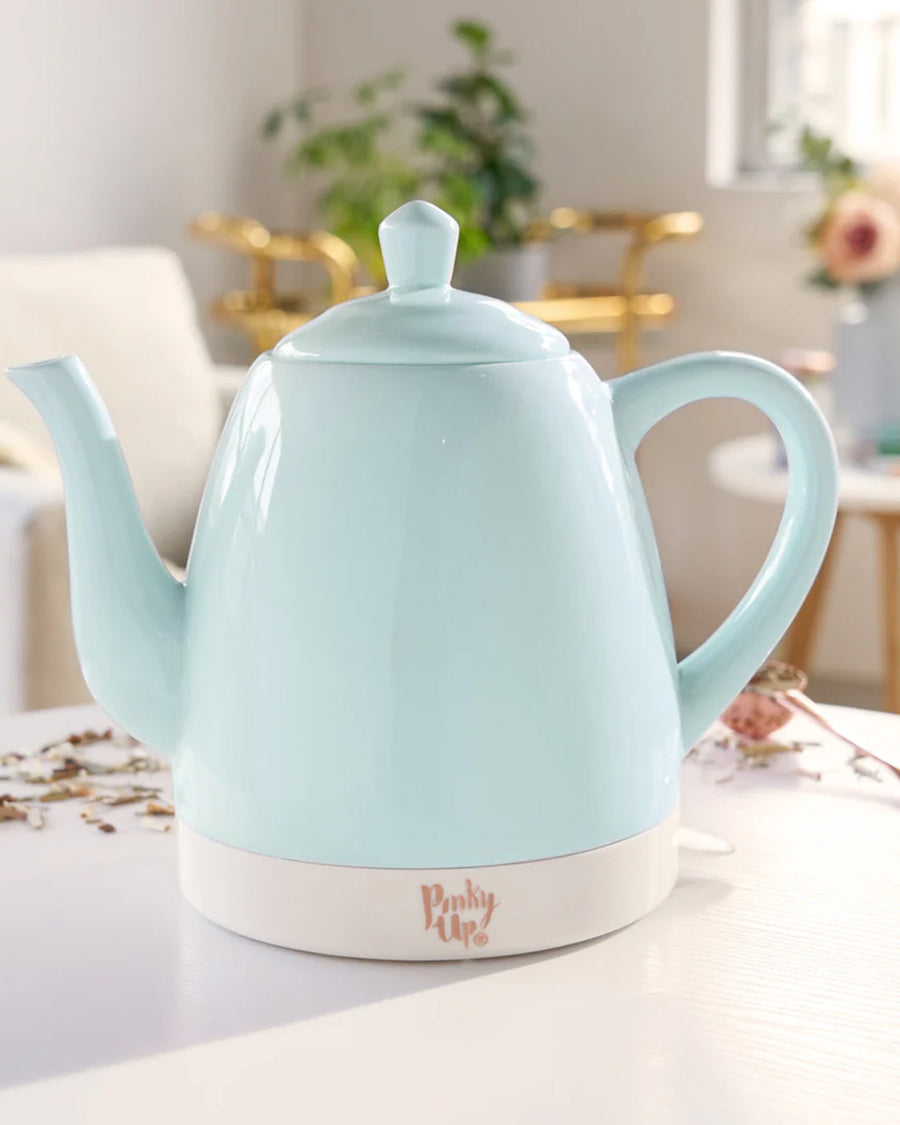 mint ceramic electric tea kettle with rose gold accents on a table