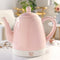 pink ceramic electric tea kettle off of rose gold base on a table