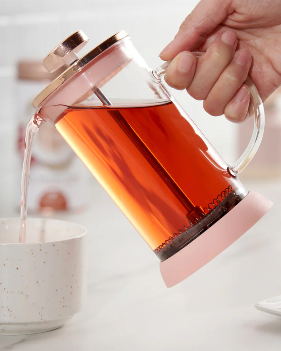 model pouring tea from rose gold mini glass tea press with silver press pieces