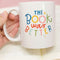 model holding white ceramic mug with colorful 'the book was better' across the front