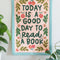 11 in. x 14 in. embroidered wall hanging with colorful flowers and'today is a good day to read a book' across the front displayed on a wall