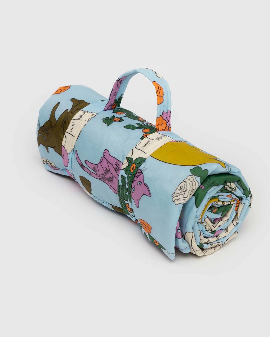 folded light blue puffy picnic blanket with colorful table cats print