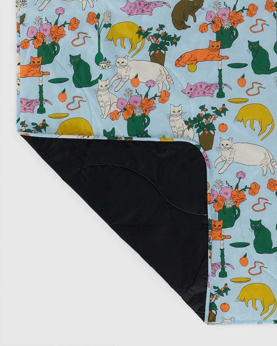 black underside of light blue puffy picnic blanket with colorful table cats print