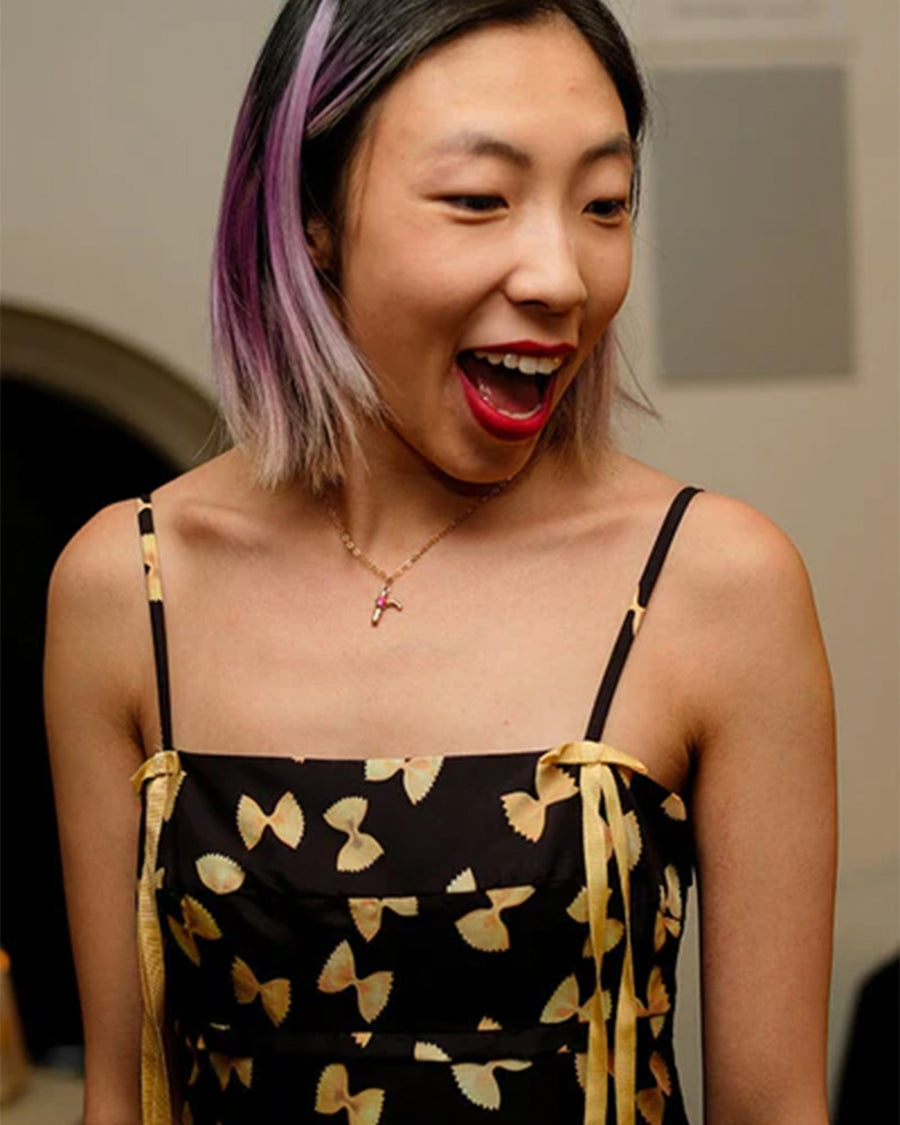 model wearing black mini dress with yellow bow tie pasta print and yellow ribbon on the straps