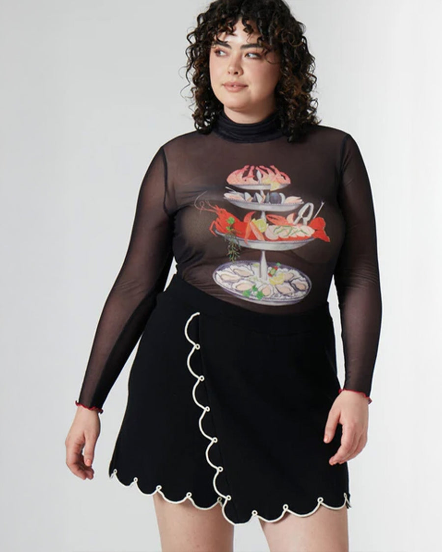 model wearing black sheer long sleeve top with turtleneck and seafood tower graphics