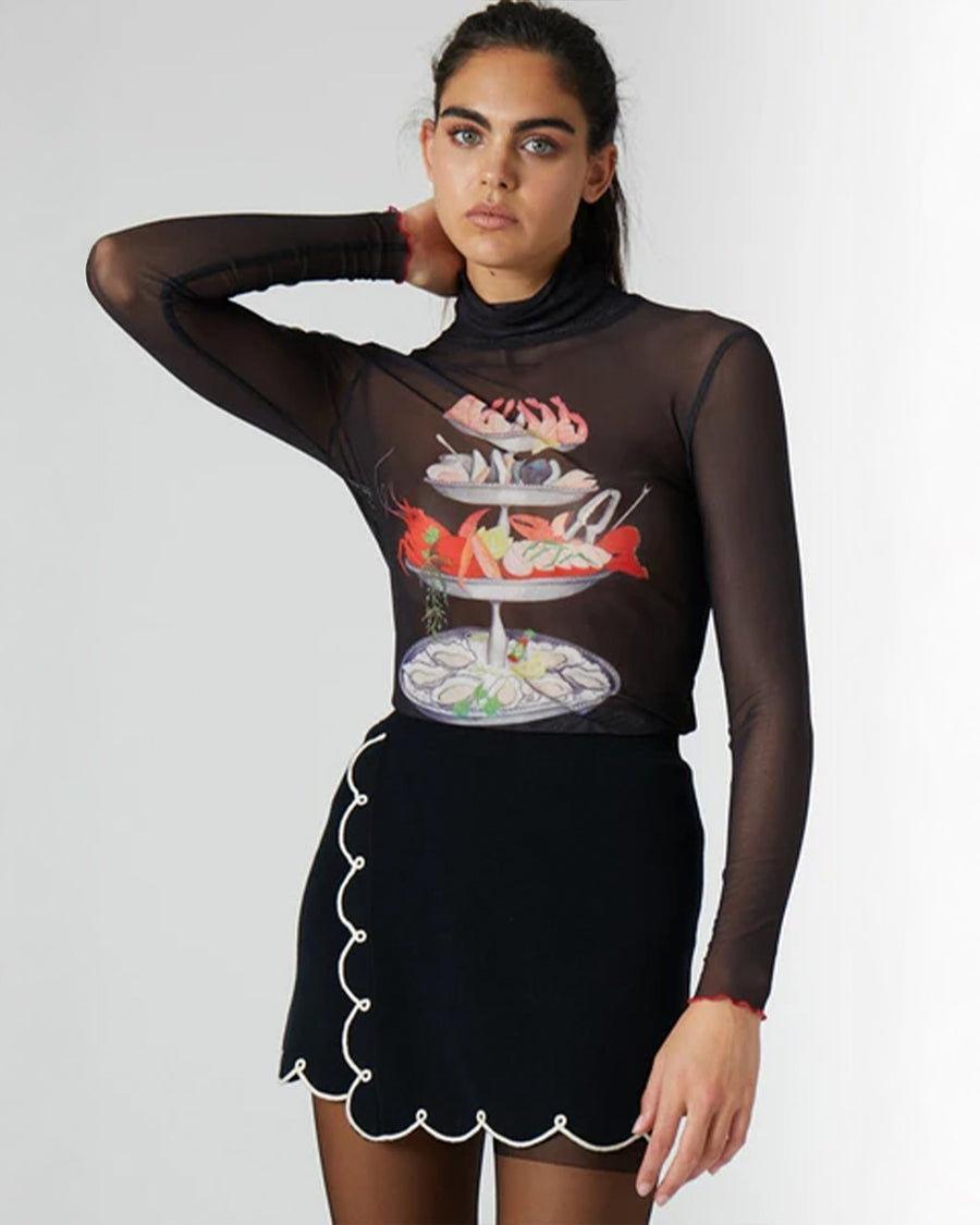 model wearing black sheer long sleeve top with turtleneck and seafood tower graphics