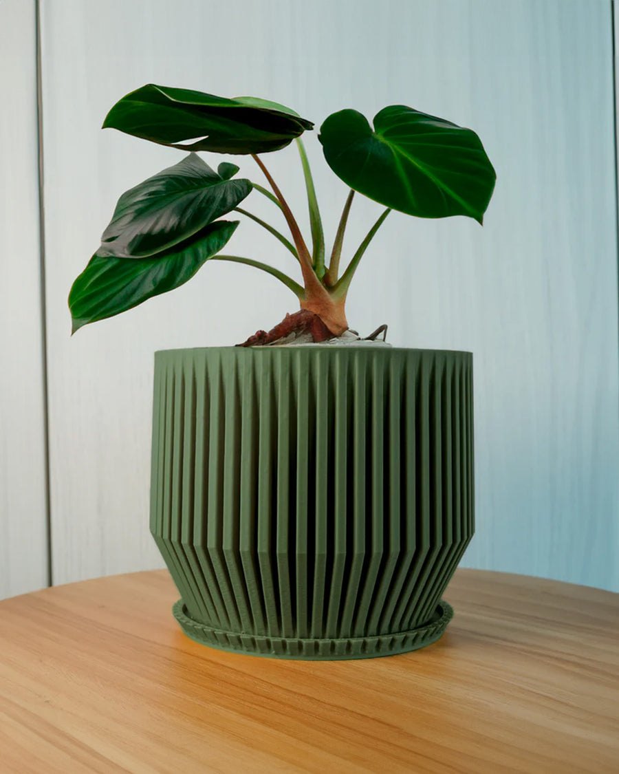 green textured 3d printed vase with a plant in it