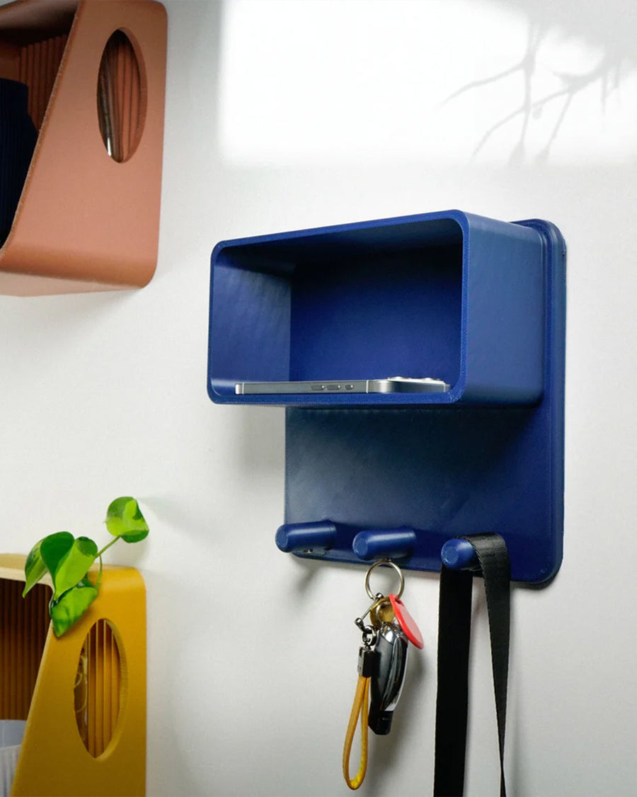 blue 3d print magnetic key ring holder  on a wall with various items inside of it