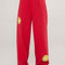 model wearing red sweatpants with yellow smiley print on legs