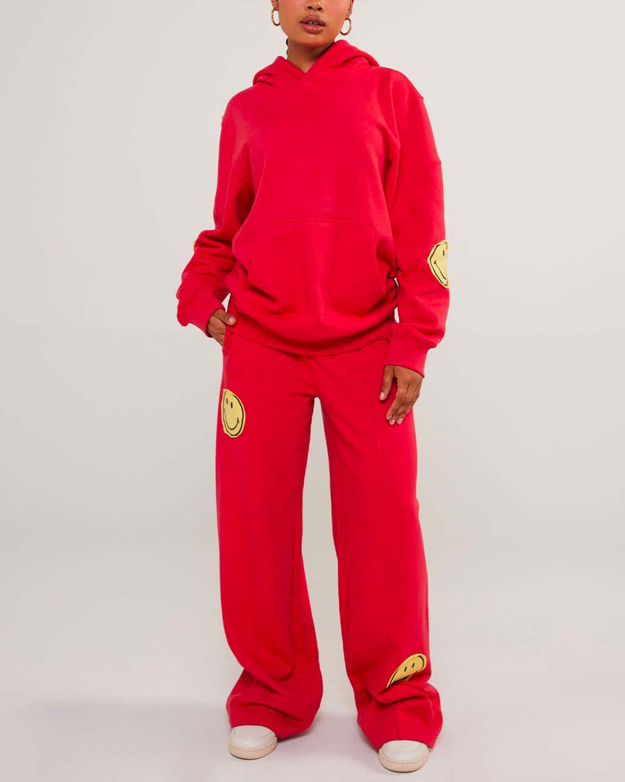 model wearing red sweatpants with yellow smiley print on legs