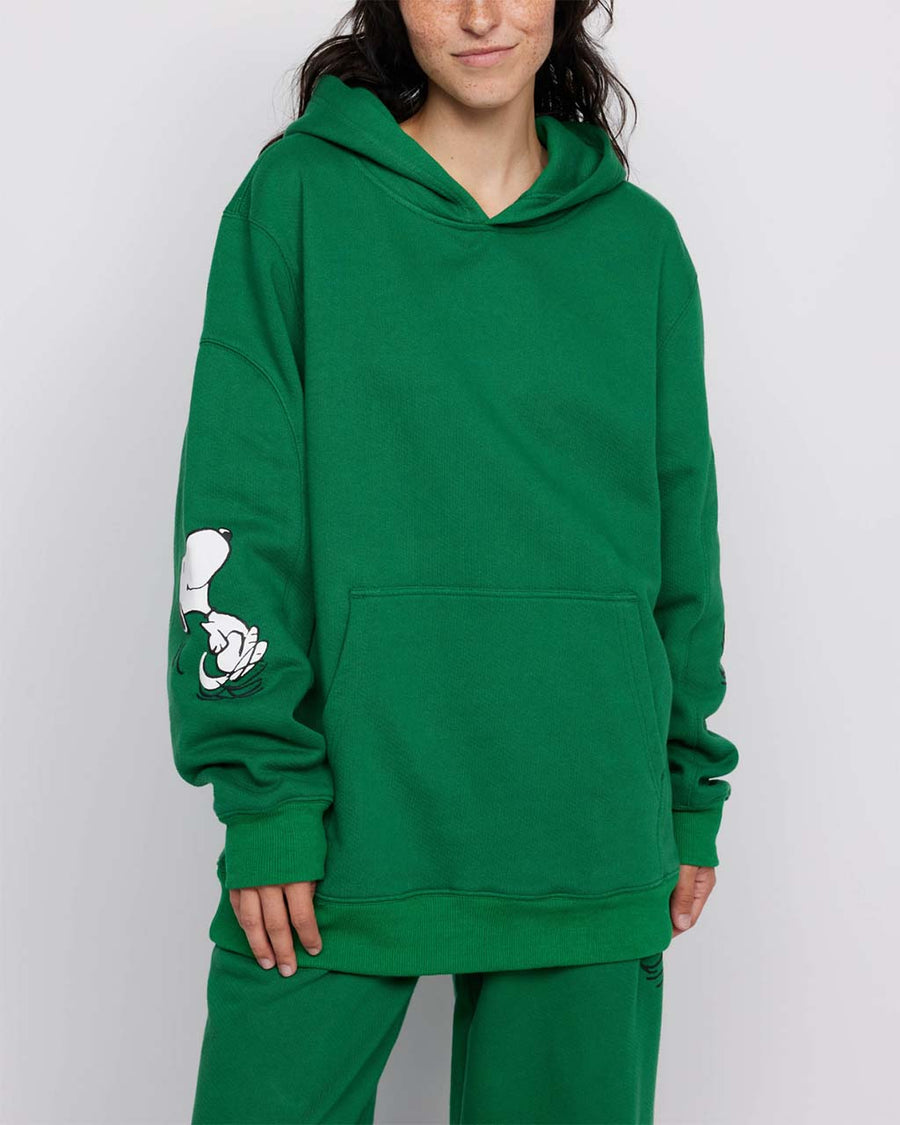 model wearing kelly green hoodie with woodstock and snoopy print on sleeves