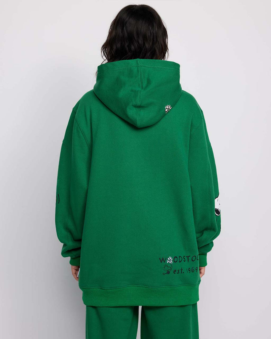 back view of model wearing kelly green hoodie with woodstock and snoopy print on sleeves