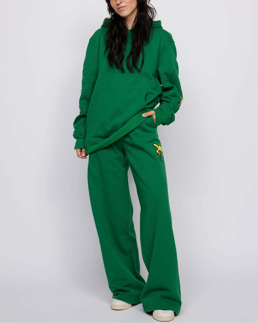 model wearing kelly green sweatpants with slit pockets and woodstock and snoopy print on sides