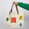 model holding tan tote bag with various peanuts inspired patches and brown canvas straps
