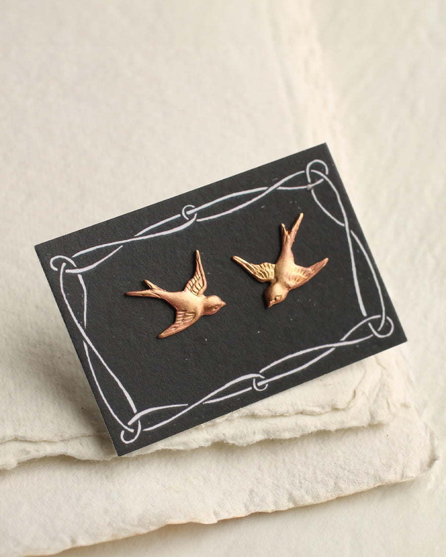 brass swallow bird shaped stud earrings on cardstock