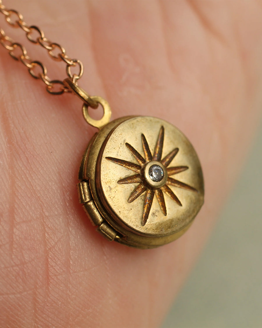 up close of gold tiny compass star locket