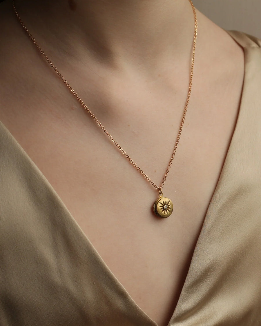 model wearing gold tiny compass star locket