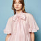 model wearing satin light pink mini dress with oversized bow neckline and flutter short sleeves 