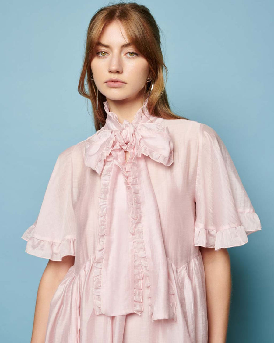 model wearing satin light pink mini dress with oversized bow neckline and flutter short sleeves 