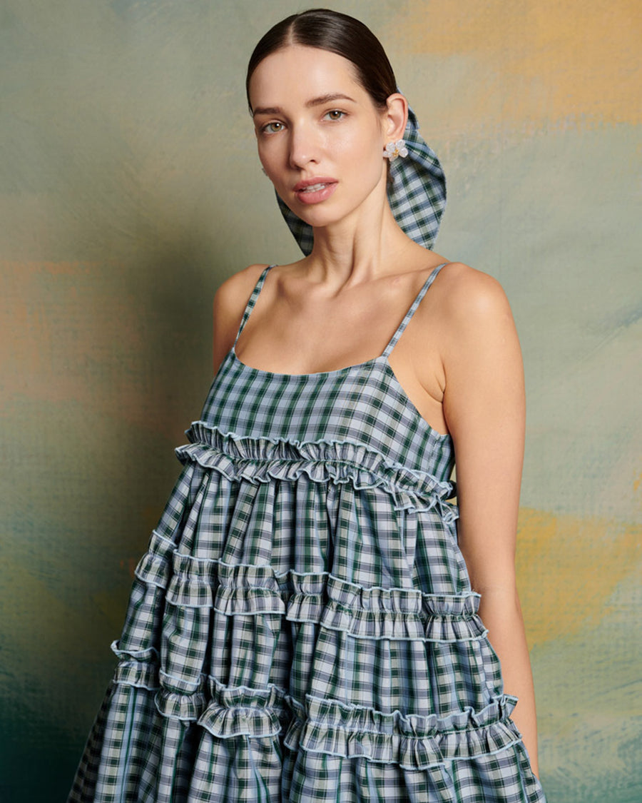 up close of model wearing blue gingham mini dress with adjustable straps and ruffle tier detail