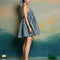 side view of model wearing blue gingham mini dress with adjustable straps and ruffle tier detail