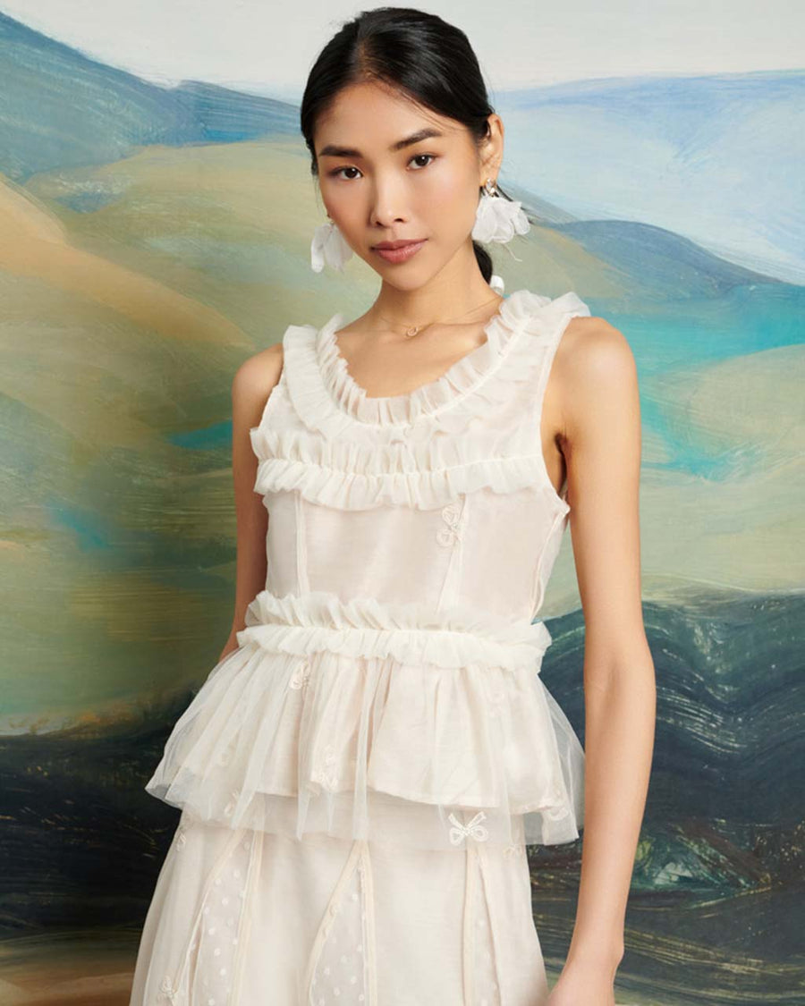 model wearing cream Peplum style top in a bow embroidered tulle fabric.