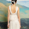 back view of model wearing cream Peplum style top in a bow embroidered tulle fabric.