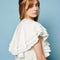 up close of model wearing white mini dress with oversized ruffle cape top