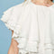 up close of front of model wearing white mini dress with oversized ruffle cape top