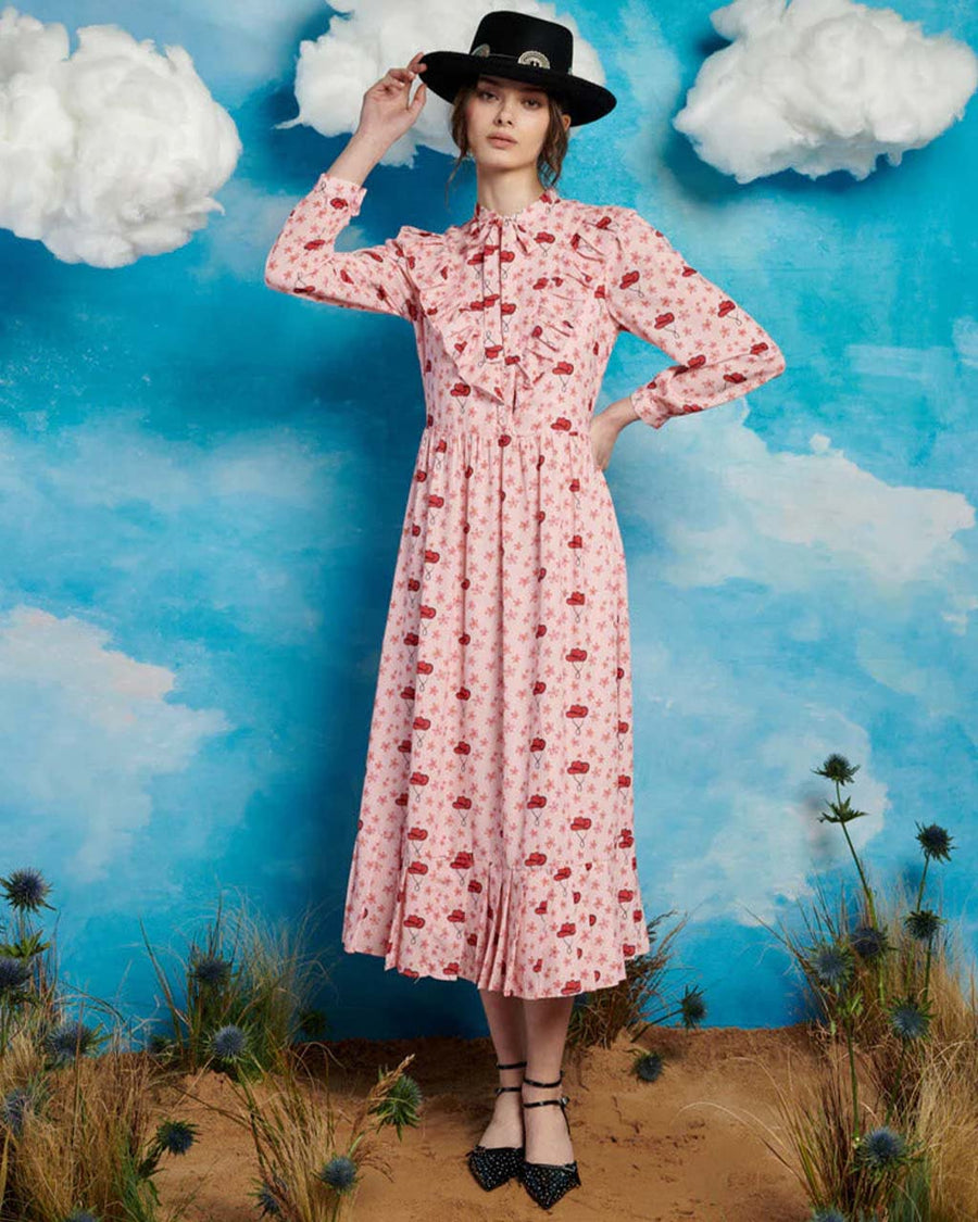 model wearing light pink midi dress with long sleeves, front yoke and tie and pink cowboy hat print