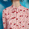 up close of model wearing light pink midi dress with long sleeves, front yoke and tie and pink cowboy hat print