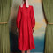 back view of model wearing red midi dress with oversized tie neckline, slight puff long sleeves and tiered skirt