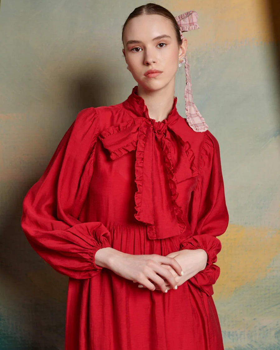 up close of model wearing red midi dress with oversized tie neckline, slight puff long sleeves and tiered skirt