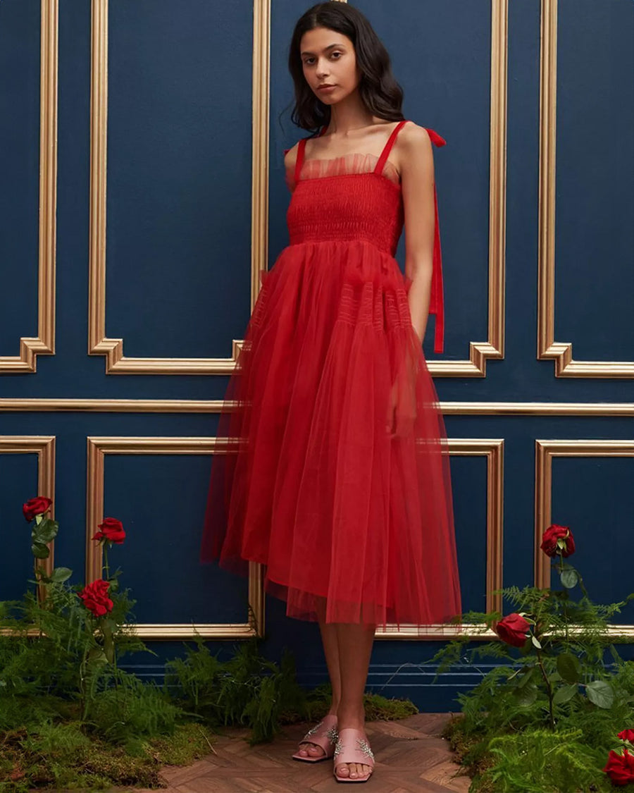 model wearing red tulle midi dress with velvet tie straps and smocked bodice