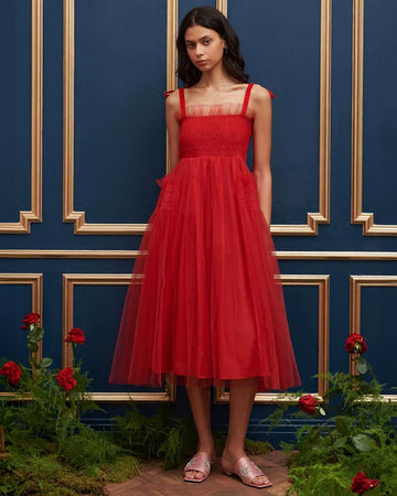 model wearing red tulle midi dress with velvet tie straps and smocked bodice