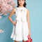 model wearing white mini dress with exaggerated bow neckline and ruffle hem 