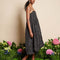 side view of model wearing black bubble hem midi dress with delicate pink flowers and open back