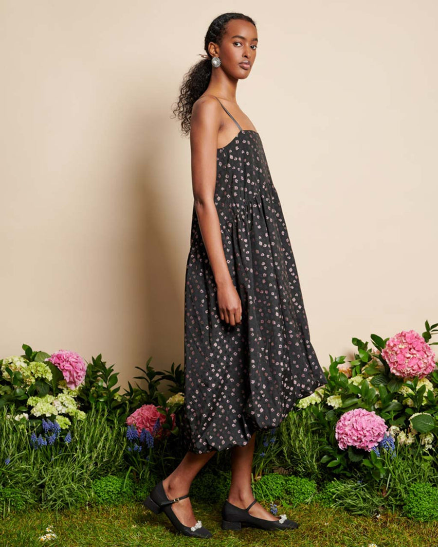 side view of model wearing black bubble hem midi dress with delicate pink flowers and open back