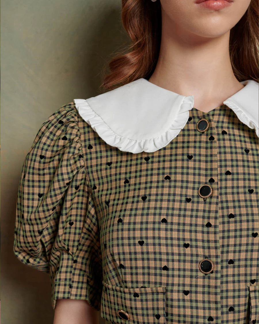 up close of model wearing green check and heart print midi dress with puff sleeves and white oversize collar, and button front