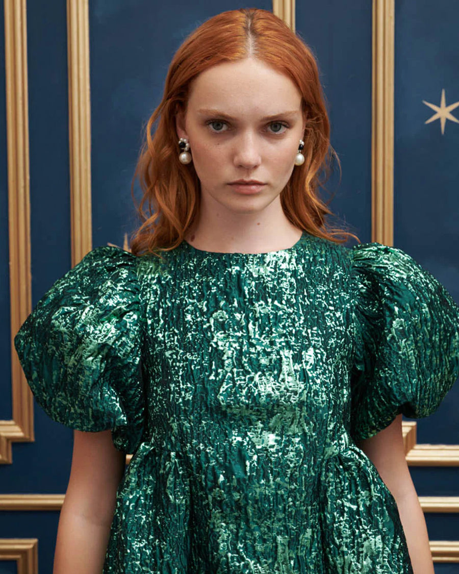 up close of model wearing emerald green jacquard mini dress with puff sleeves and bubble hem