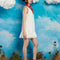 side view of model wearing white mini dress with ruffle hem and deep v neckline