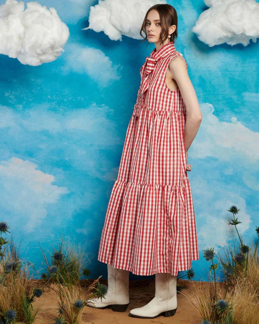 side view of model wearing red and white gingham maxi dress with tiered skirt and oversized bow