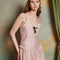 up close of model wearing light pink midi dress with black bow on the bust and ruffle material on the hips