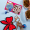 keychain with oversized red chenille bow next to lotto tickets and sunglasses