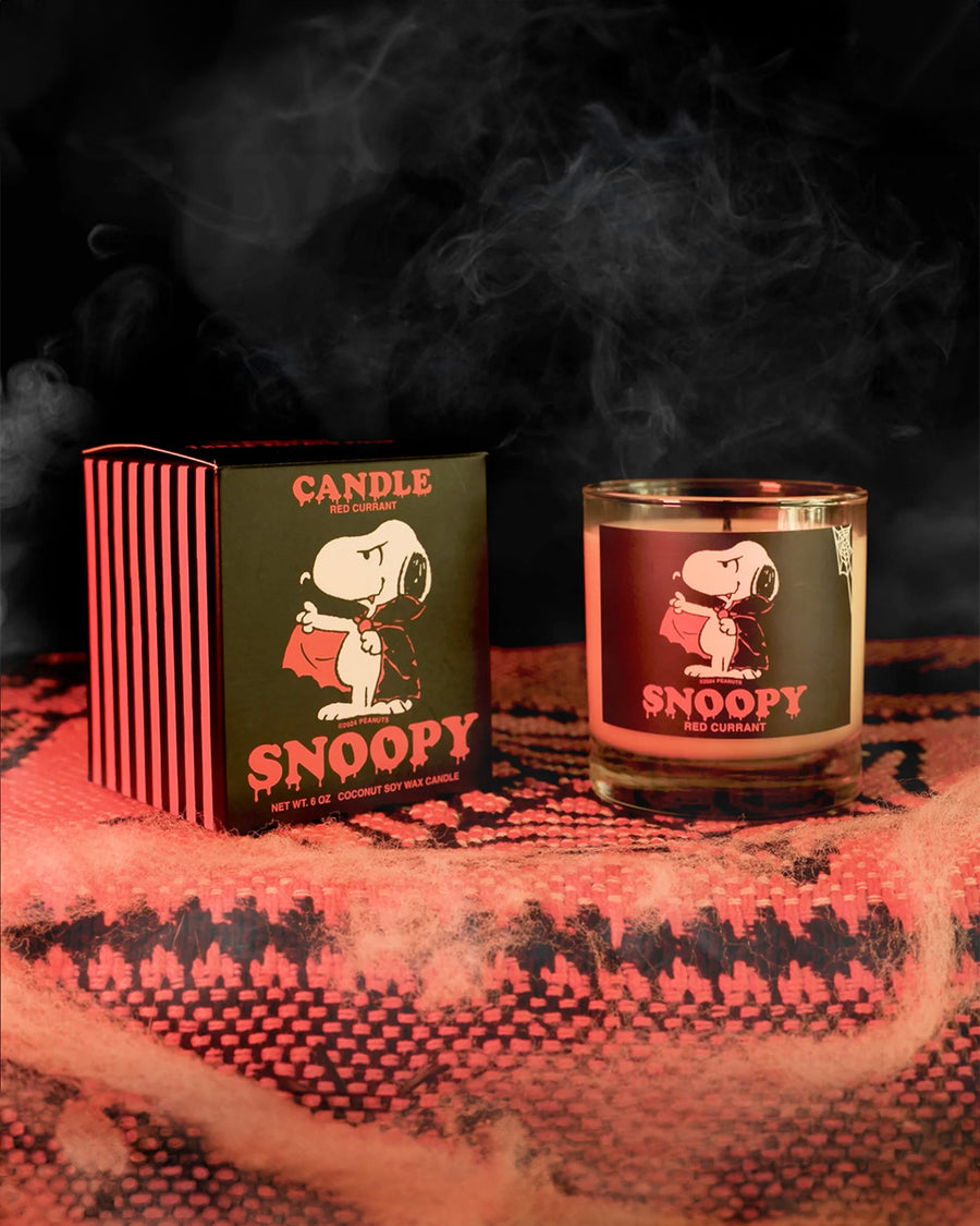 red currant scented candle with dracula snoopy on the candle and box in a halloween setting