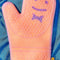 up close of orange silicone oven mitt with smiley detail