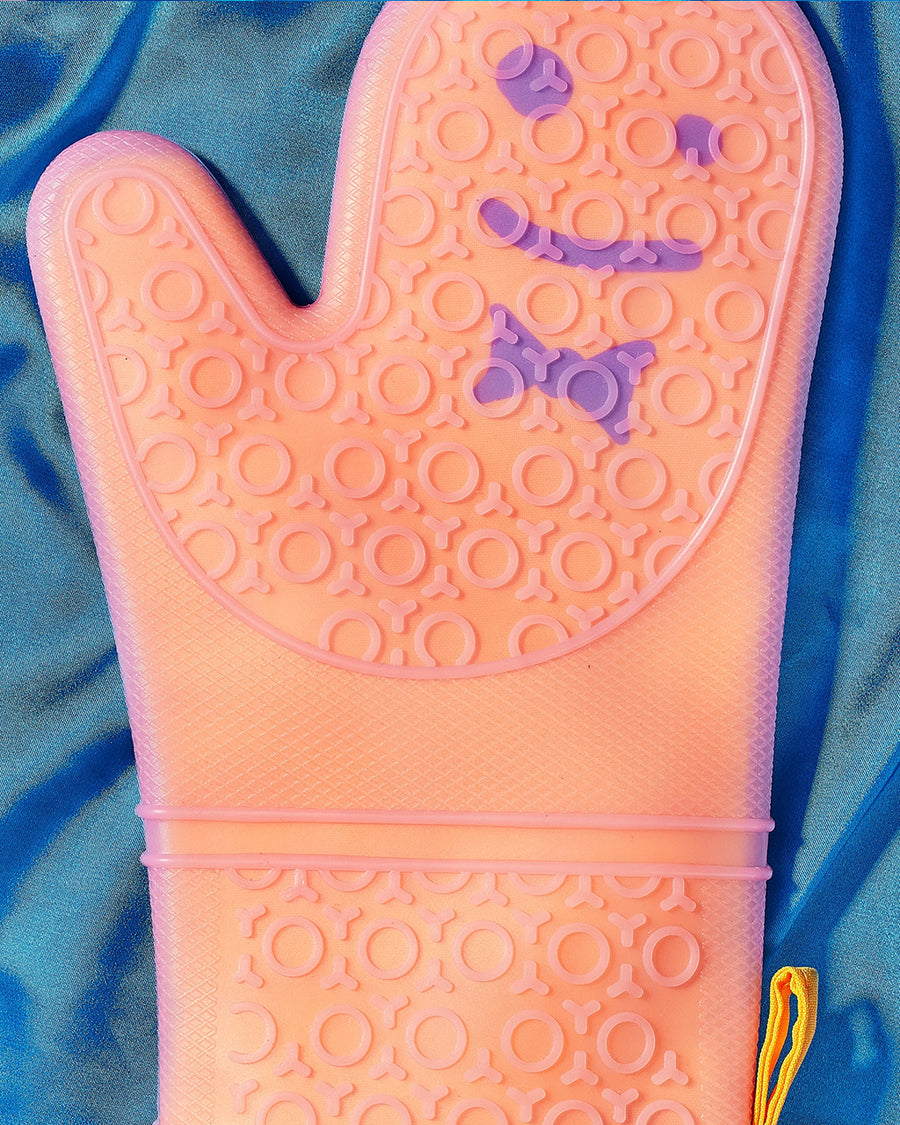 up close of orange silicone oven mitt with smiley detail