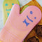 set of 2 orange and pink silicone oven mitts with smiley face detail on a cutting board